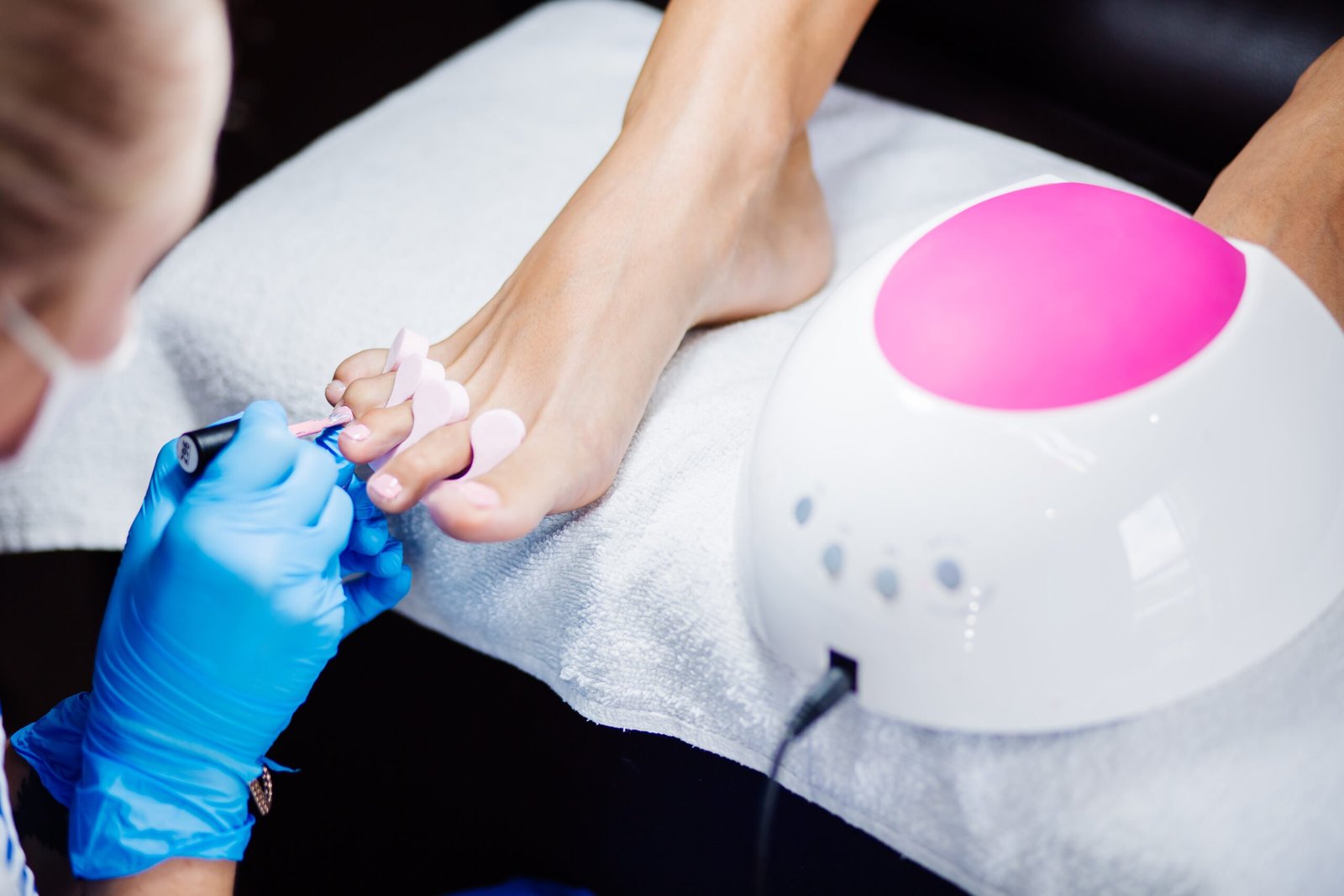 home-salon-pedicure-foot-care-treatment-nail-process-professional-pedicures-master-blue-gloves-apply-light-pink-gel-polish